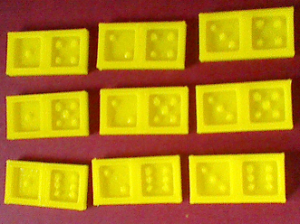 einige gelbe 3D-gedruckte Dominosteine auf rotem Grund